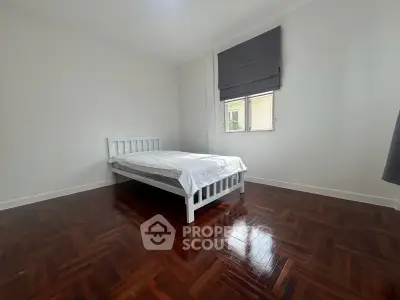 Spacious bedroom with wooden flooring and minimalist decor in a modern apartment.