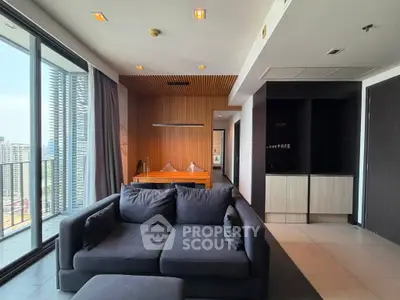 Modern living room with city view, featuring sleek furniture and floor-to-ceiling windows.