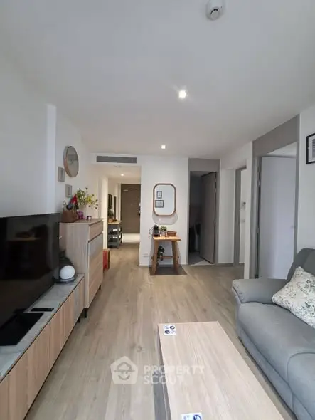 Modern living room with stylish decor and open layout, featuring a cozy sofa and sleek wooden furniture.
