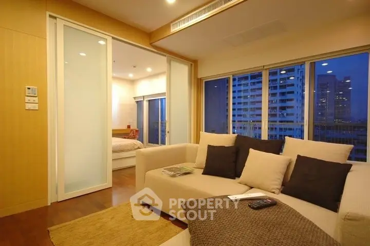 Modern living room with cozy sofa and city view, sliding doors to bedroom.