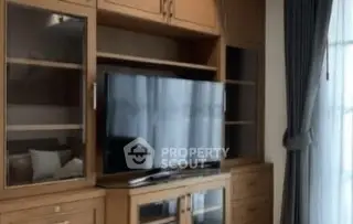 Spacious living room with elegant wooden entertainment center and large TV