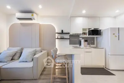 Modern open-layout kitchen and living room with sleek white cabinetry and cozy seating area.