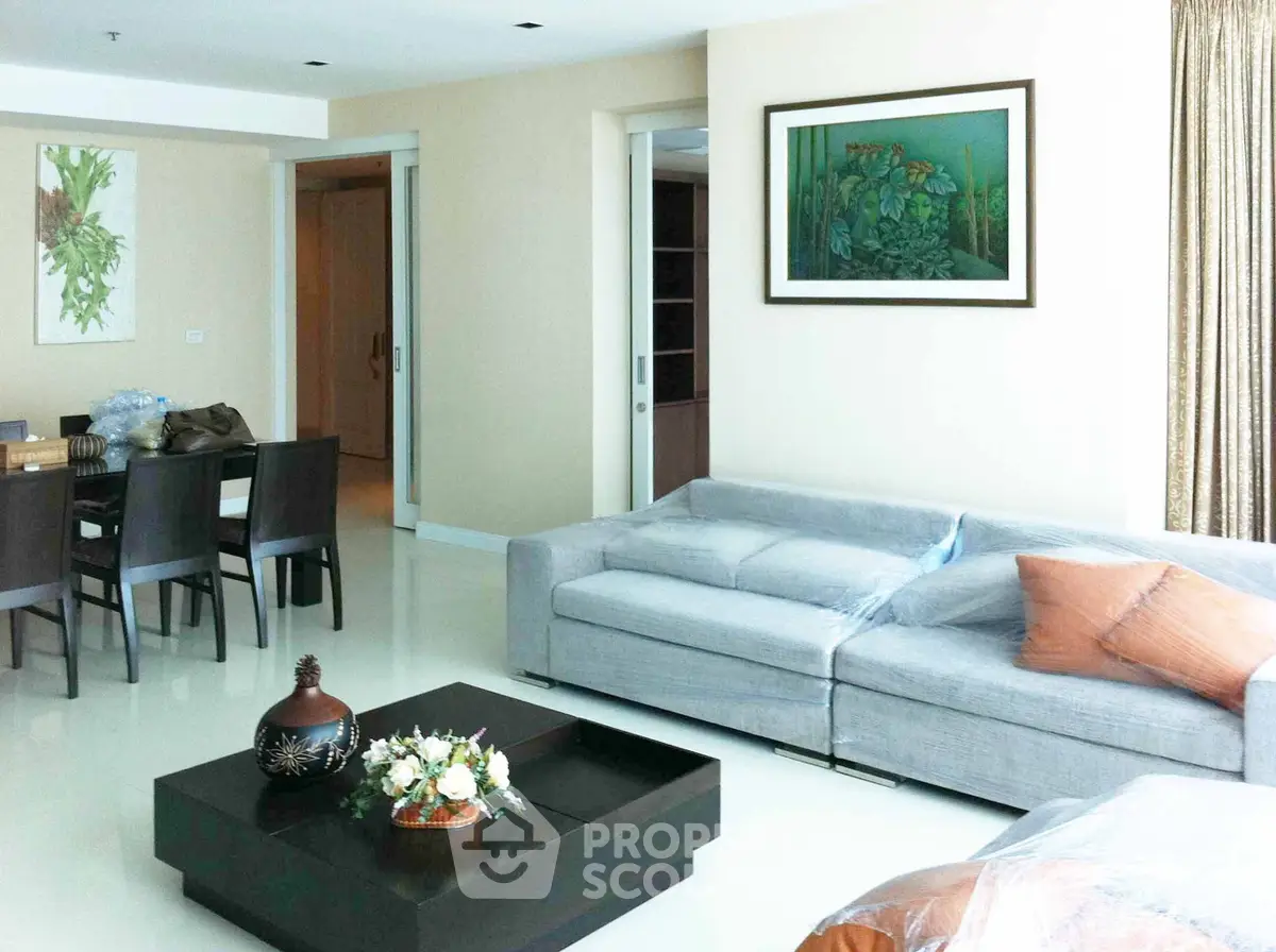 Spacious modern living room with elegant decor and dining area, featuring a cozy sofa and stylish artwork.