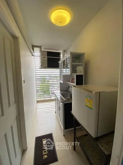 Compact kitchen with fridge and cabinets in cozy apartment