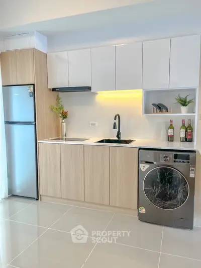 Modern kitchen with sleek cabinets, fridge, and washing machine in a stylish apartment.