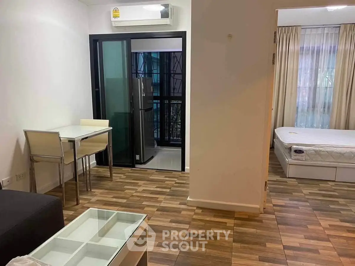 Modern apartment interior with open layout, featuring a cozy living area and a glimpse of the bedroom.