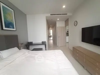 Modern bedroom with sleek furniture and wall-mounted TV in a stylish apartment.