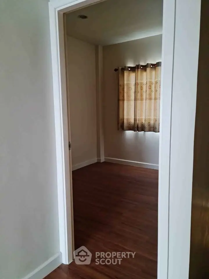 Cozy empty room with wooden flooring and elegant curtains, perfect for a personalized touch.