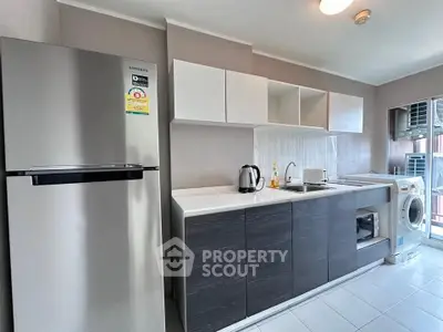 Modern kitchen with sleek cabinets, fridge, and washing machine in a stylish apartment.