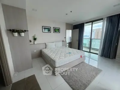 Spacious bedroom with modern decor and city view balcony access.