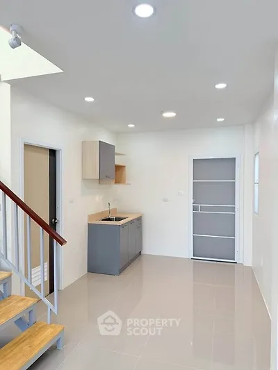 Modern minimalist kitchen with sleek cabinetry and staircase in bright open space