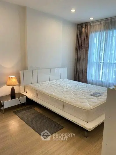 Modern bedroom with large window and stylish lamp in a cozy apartment.