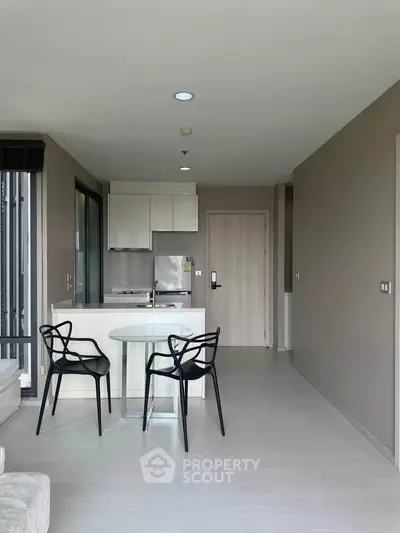 Modern open-plan living room with sleek kitchen and stylish dining area in a contemporary apartment.