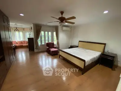 Spacious bedroom with elegant wooden flooring and large windows for natural light.