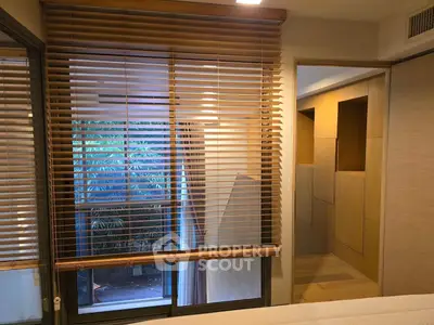 Modern bedroom with wooden blinds and view of lush greenery
