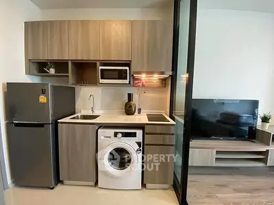 Modern compact kitchen with washing machine and microwave in stylish apartment.