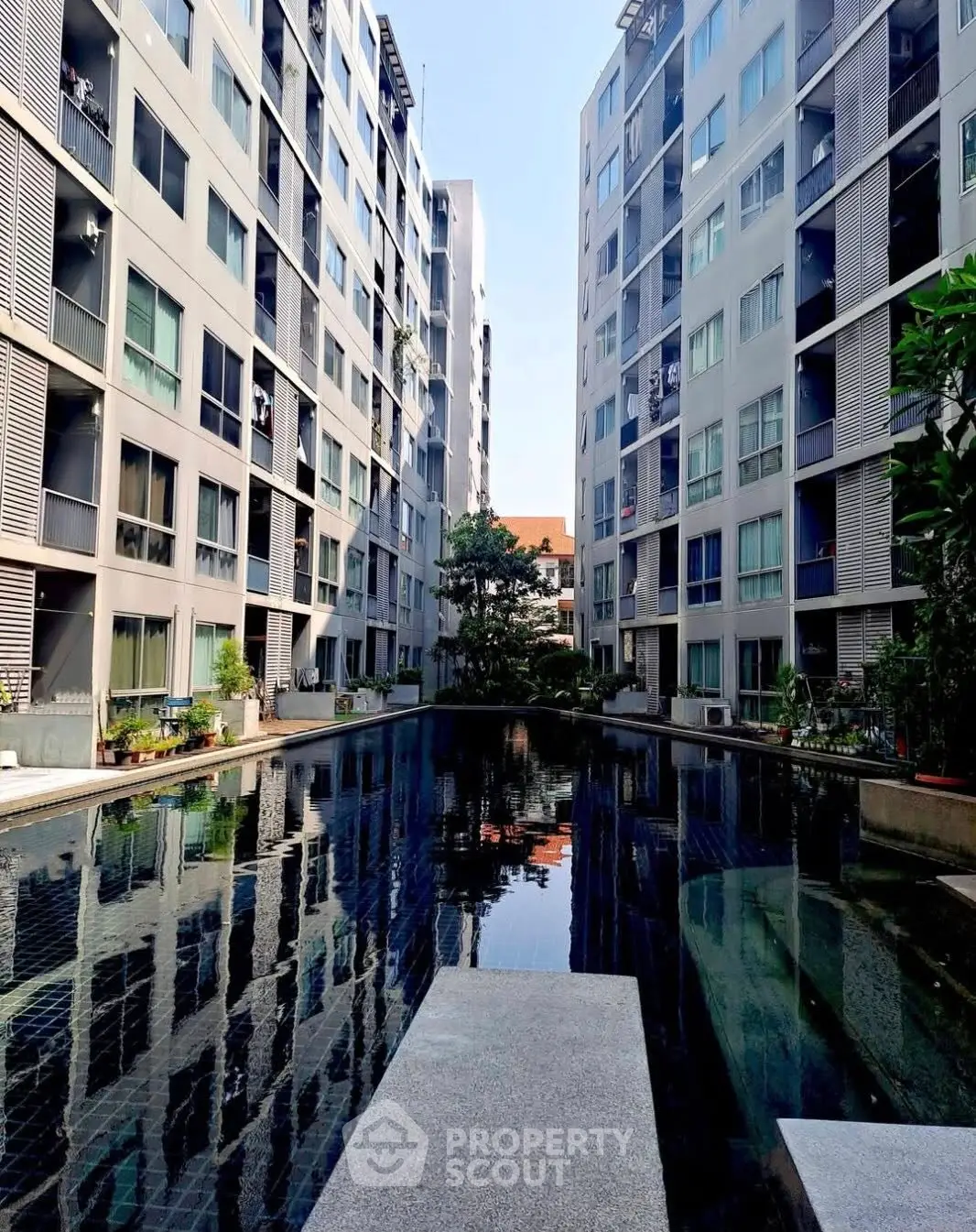Modern apartment complex with central pool and lush greenery