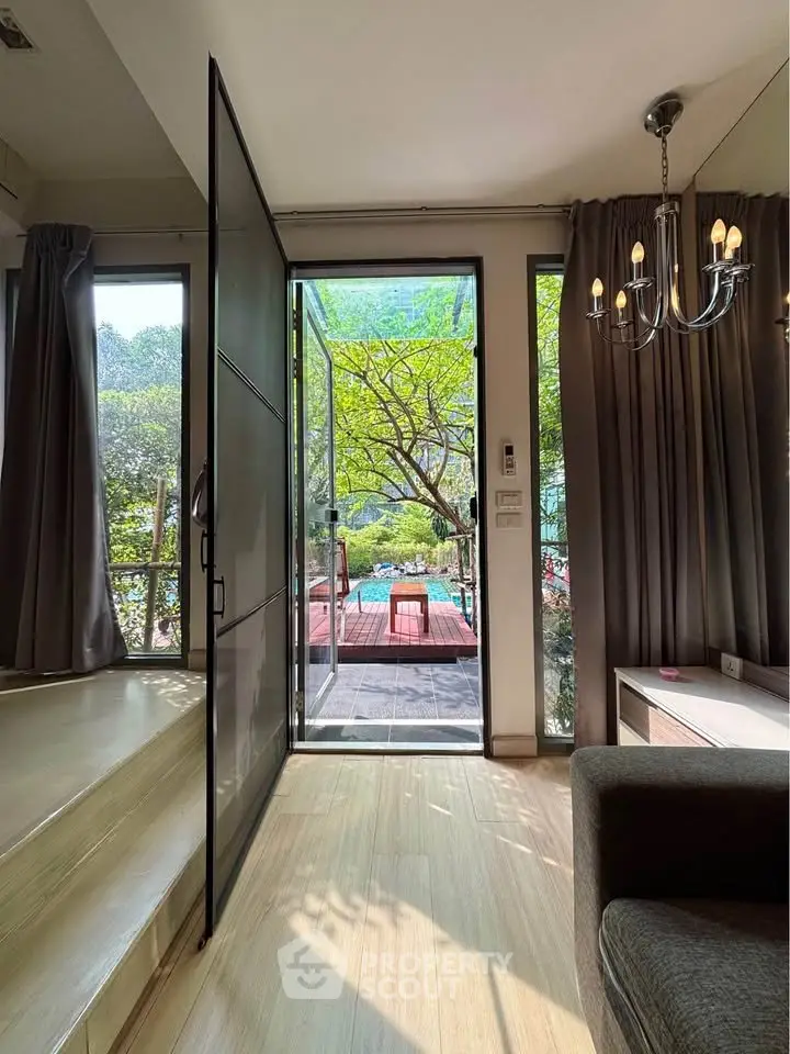 Charming living room with garden view and elegant chandelier, perfect for relaxation and entertaining.