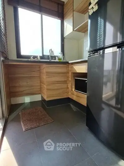 Modern kitchen with sleek black fridge and wooden cabinetry