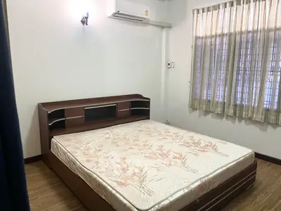 Cozy bedroom with wooden bed frame and large window for natural light.