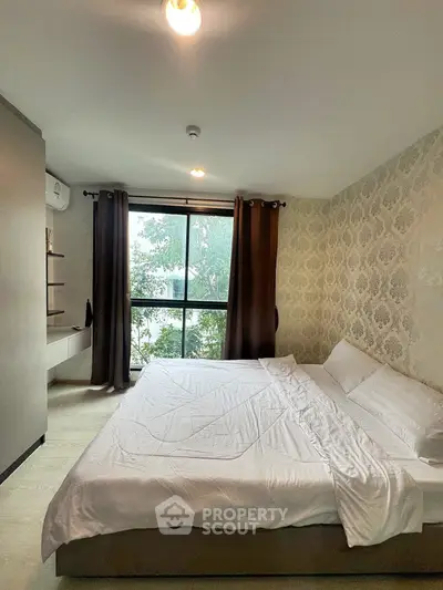 Cozy bedroom with elegant wallpaper and large window view.