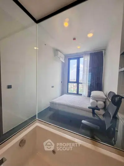 Modern bedroom with glass wall and city view, featuring a bathtub and sleek furnishings.