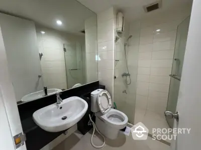 Modern bathroom with sleek design, featuring a shower, toilet, and sink in a tiled setting.