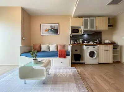 Modern studio apartment with cozy living area and compact kitchen featuring washing machine.