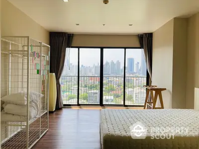 Spacious bedroom with large windows offering a panoramic city view, hardwood flooring, and ample natural light, perfect for relaxation and comfort.