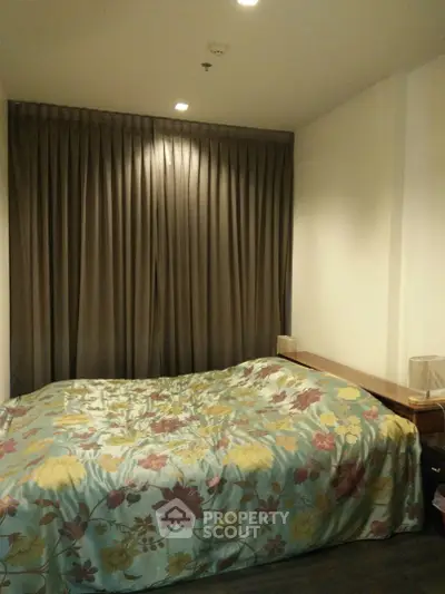 Cozy bedroom with floral bedding and elegant curtains in a modern apartment.