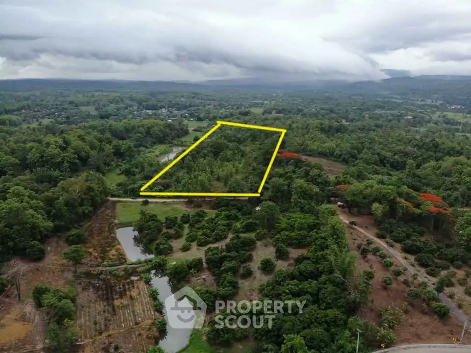 Expansive aerial view of lush green land with outlined property boundary, ideal for development.
