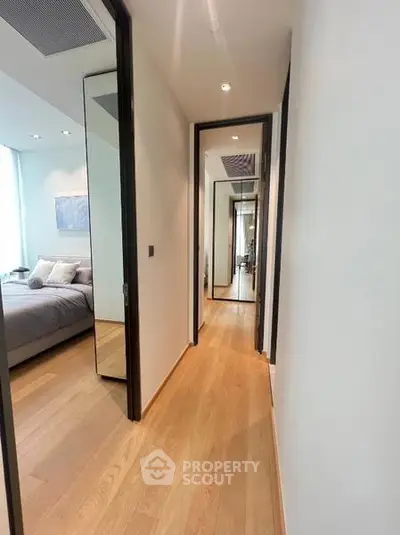 Modern apartment hallway with wooden flooring leading to a cozy bedroom