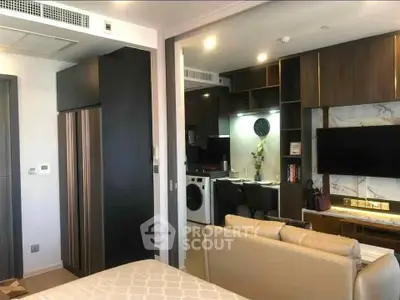 Modern studio apartment with open kitchen and stylish living area, featuring built-in appliances and elegant decor.