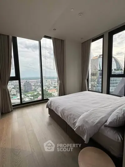 Luxurious bedroom with panoramic city views and floor-to-ceiling windows in a modern high-rise apartment.