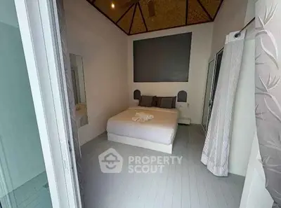 Cozy bedroom with modern decor and high ceiling, perfect for relaxation.