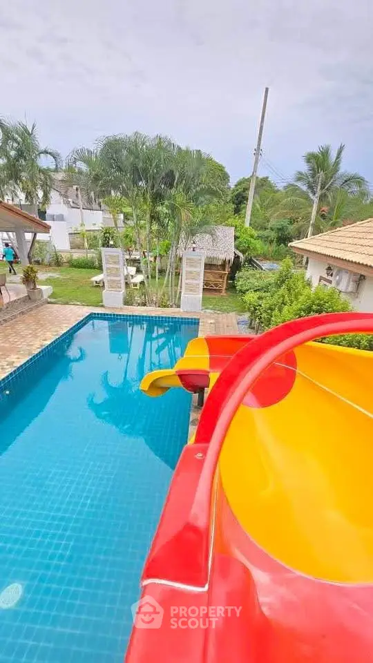 Luxurious pool area with vibrant slide and lush greenery, perfect for family fun and relaxation.