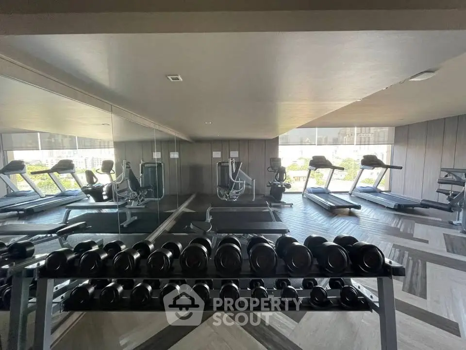 Modern gym with state-of-the-art equipment and mirrored walls in luxury building.