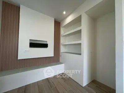 Modern minimalist living room with built-in shelves and wood panel accent wall.