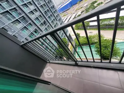 Modern high-rise building view from balcony overlooking pool and cityscape.