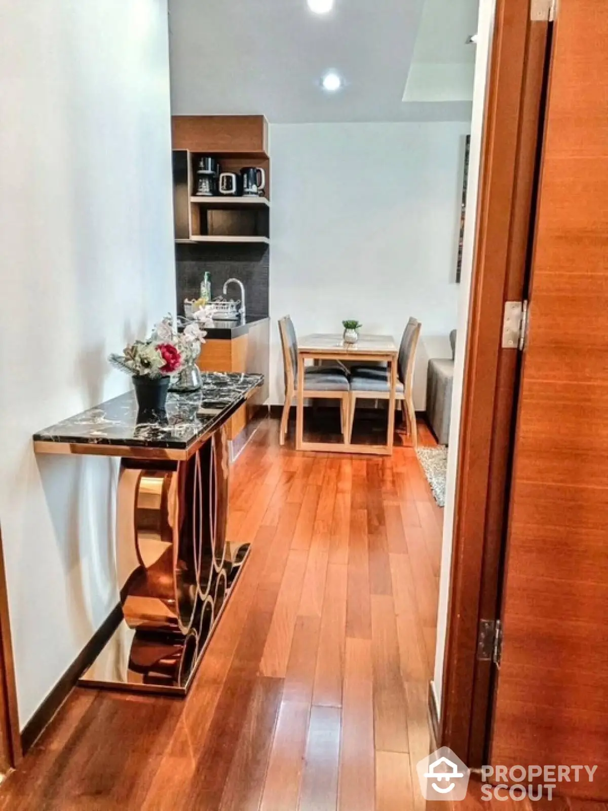 Stylish apartment hallway leading to cozy dining area with wooden flooring and elegant decor.