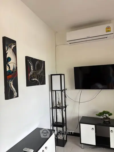 Modern living room with wall-mounted TV, air conditioner, and abstract art decor.