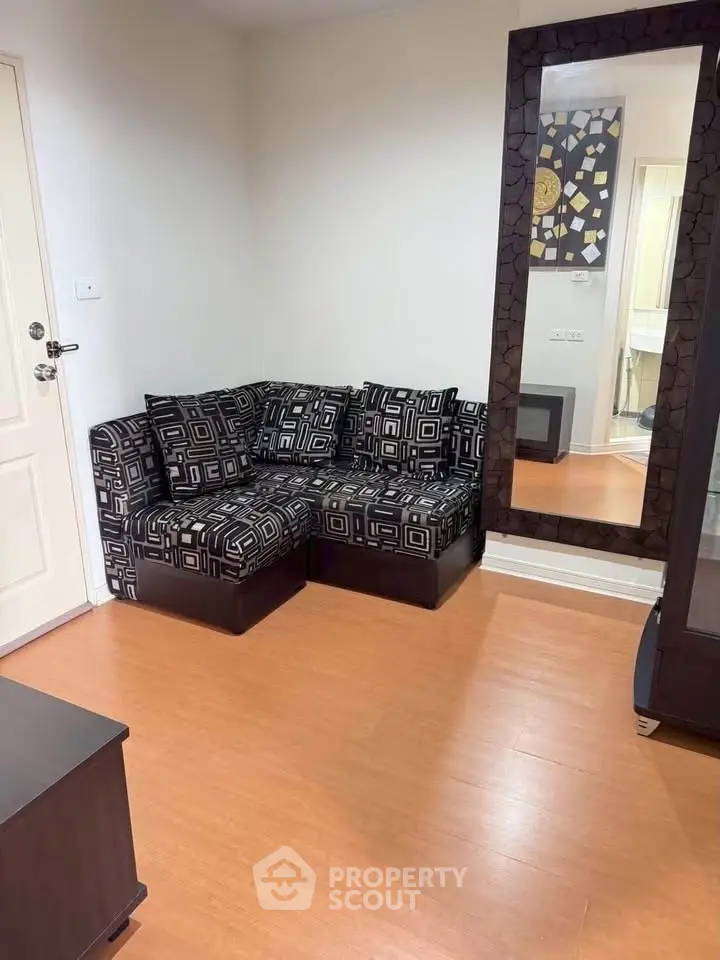 Cozy living room with modern geometric-patterned sofa and large decorative mirror.