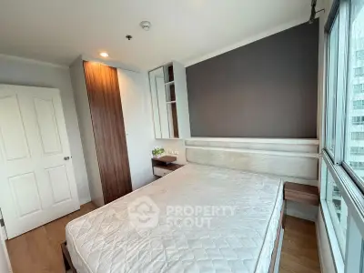 Modern bedroom with large window and built-in wardrobe in a high-rise apartment.