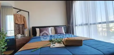 Modern bedroom with large window and stylish decor in urban apartment.