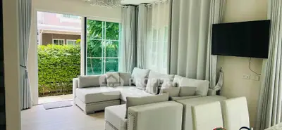 Spacious living room with modern decor and large windows overlooking lush greenery.