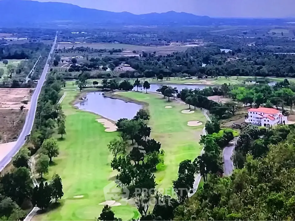 Stunning aerial view of a lush golf course with scenic mountain backdrop, perfect for luxury real estate development.