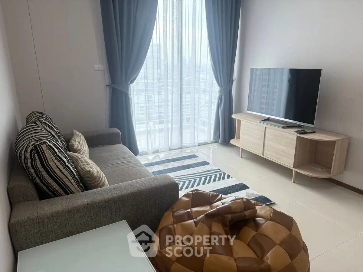 Modern living room with stylish sofa, TV, and city view through large windows.