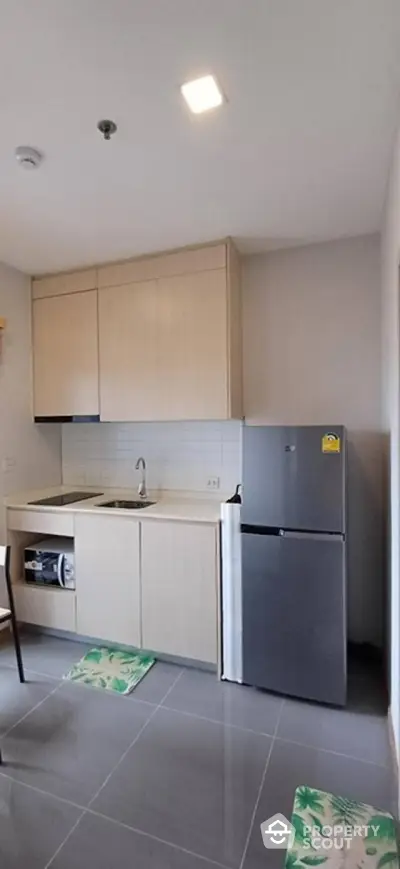 Modern kitchen with sleek cabinetry and stainless steel fridge in compact layout