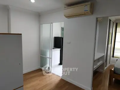 Modern apartment interior with wooden flooring and air conditioning, featuring a compact kitchen area.