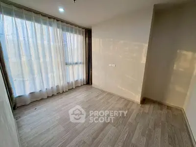 Spacious empty room with large window and wooden flooring, perfect for customization.